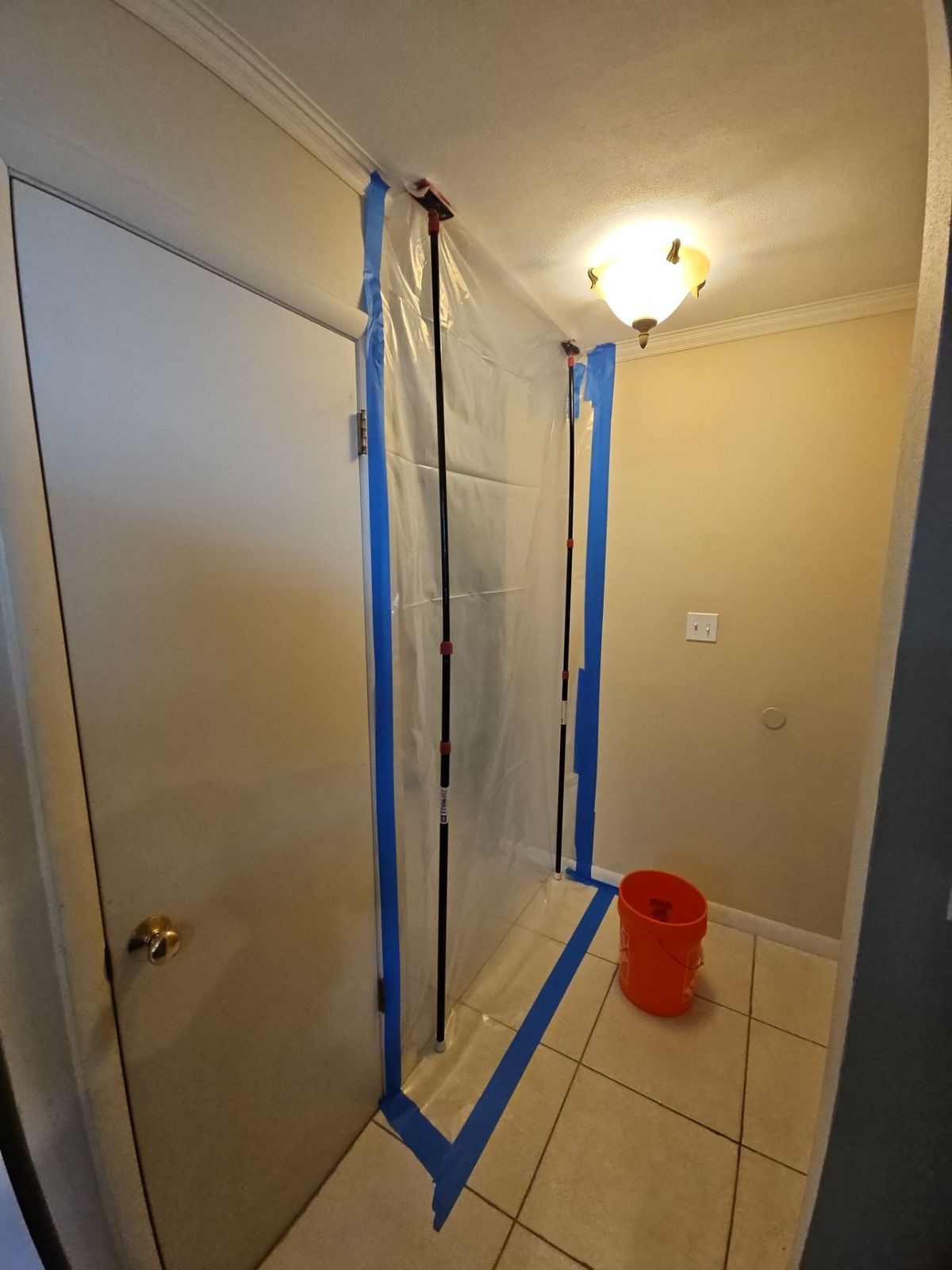 Plastic containment sealed across a kitchen doorway with blue tape before mold removal in a Titusville home