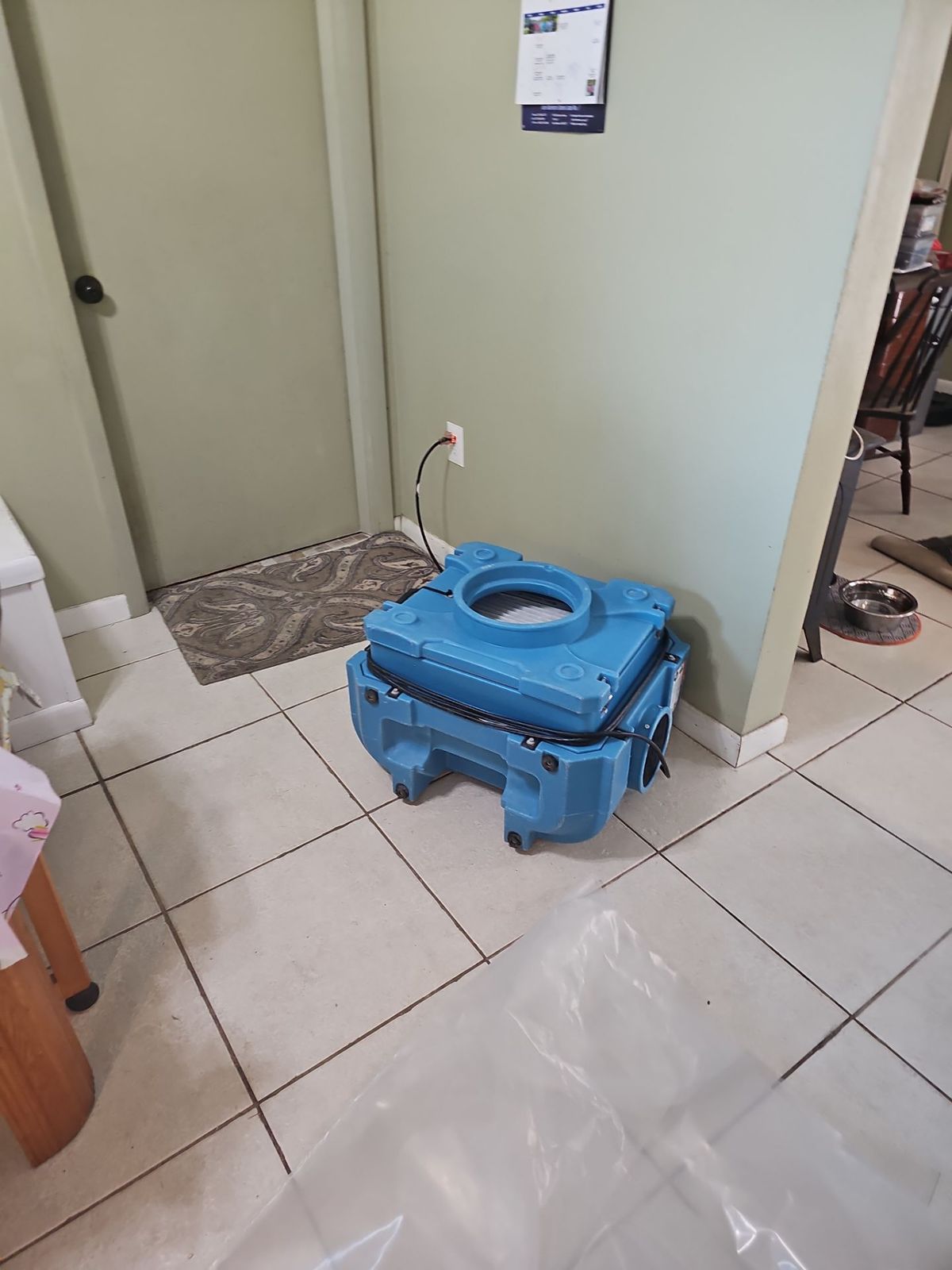 Blue HEPA air scrubber running on a tile floor outside the containment during a Titusville mold remediation