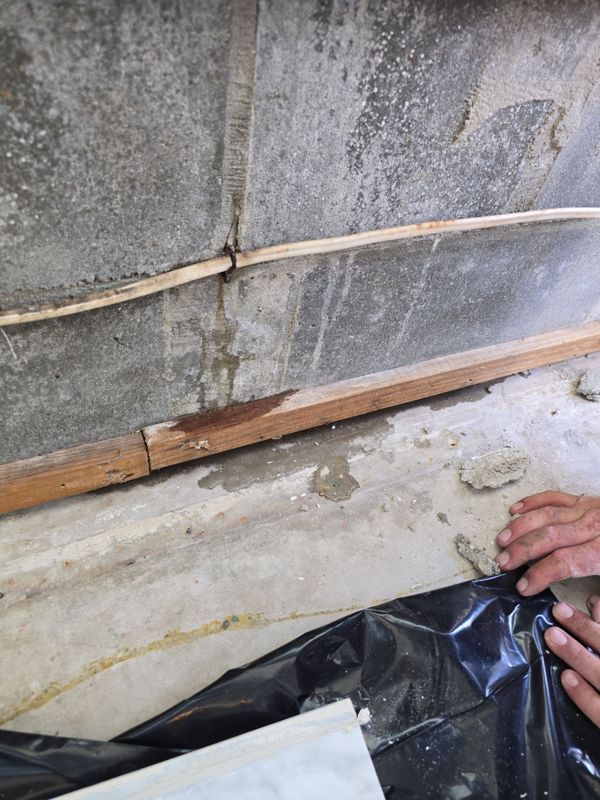 Block wall and wood strip below a window showing water staining from a leak